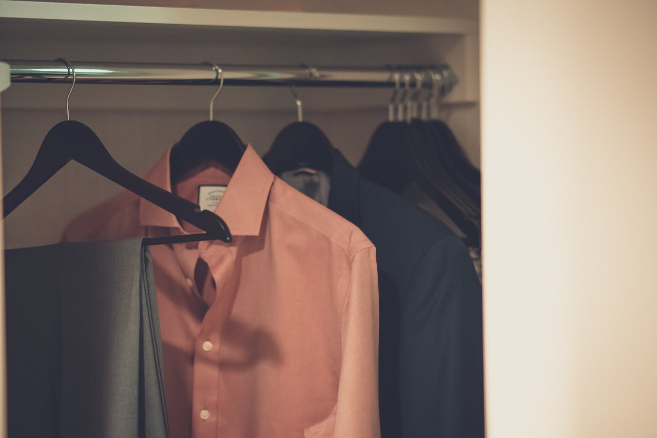 gallery-01 Stylish men's wardrobe featuring a formal suit and pink dress shirt neatly hung on hangers.